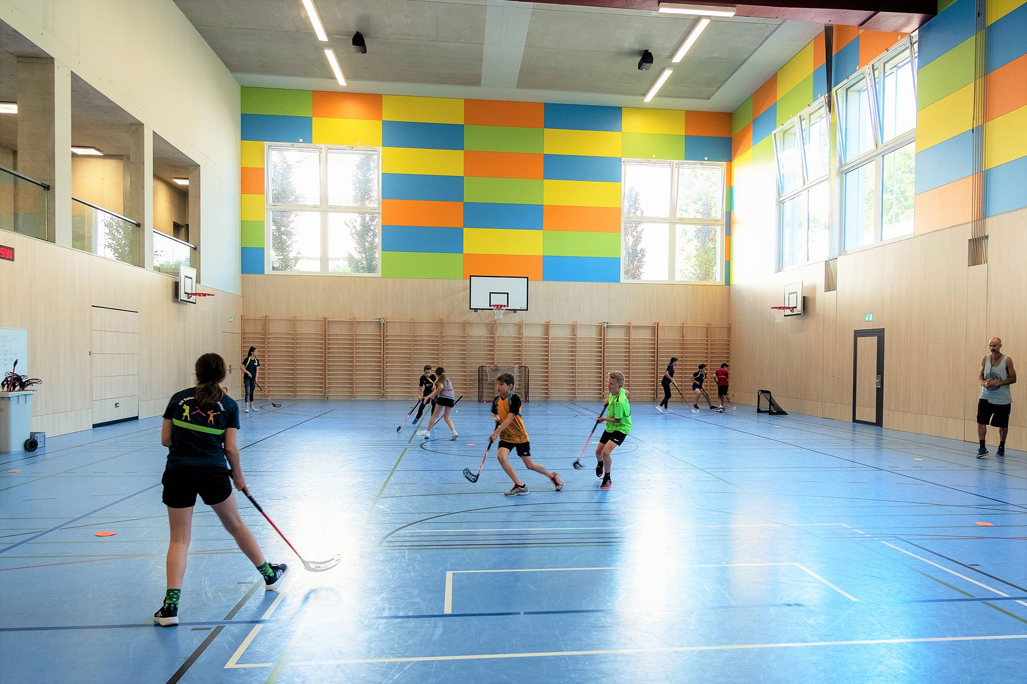 Students play floorball in the school indoor sports hall.	