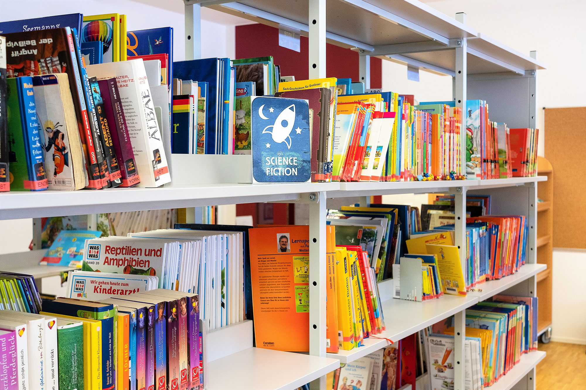 Coloured books are on the bookshelf in the library.	