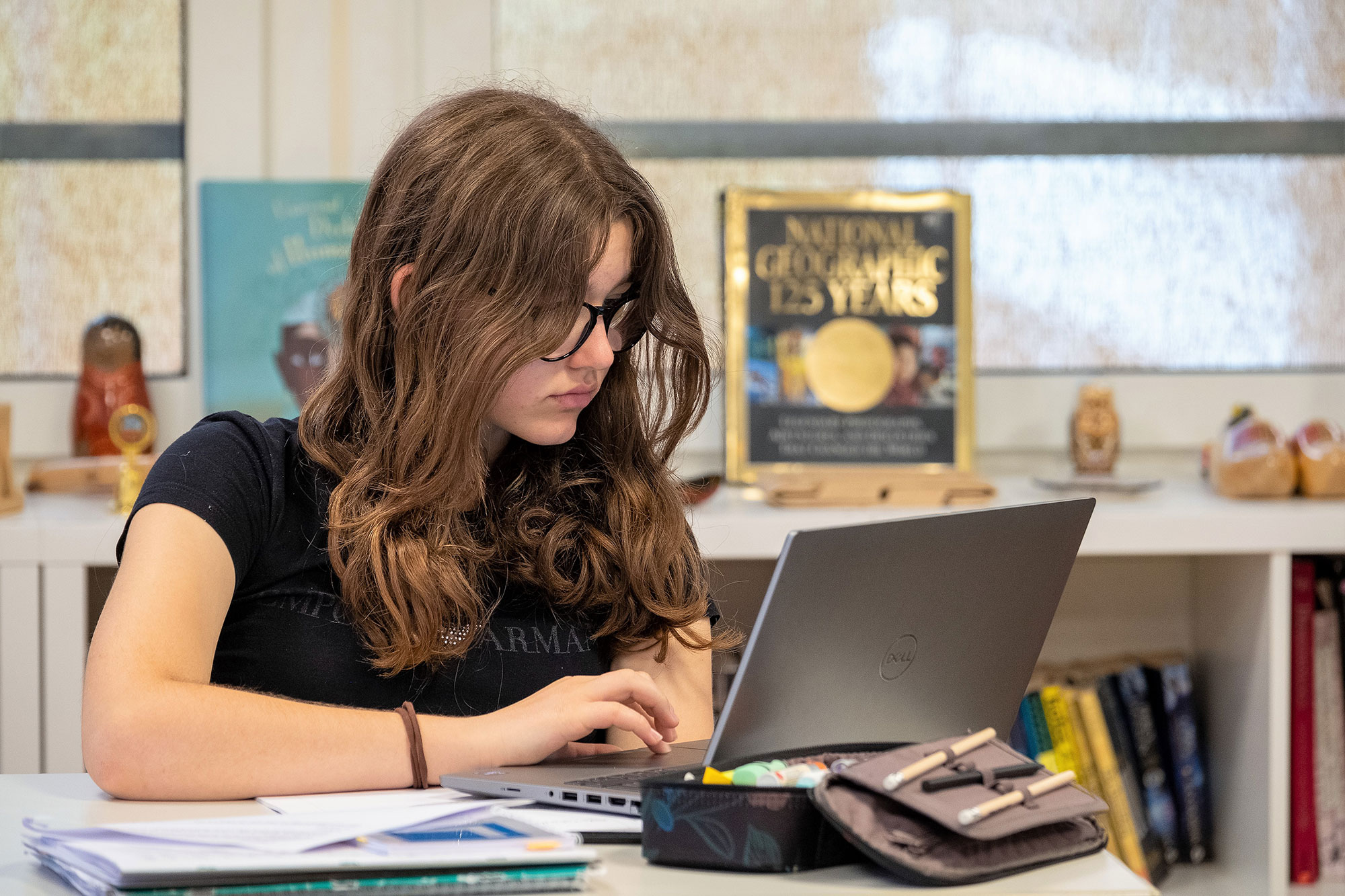 Eine Sekundarschülerin sitzt an ihrem Pult und schaut in ihren Laptop.	
