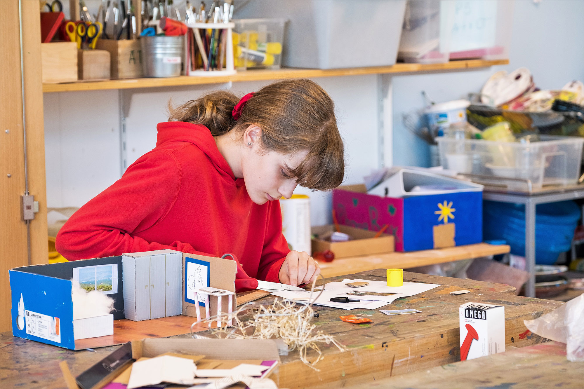 A girl is making something in the school's craft room.	