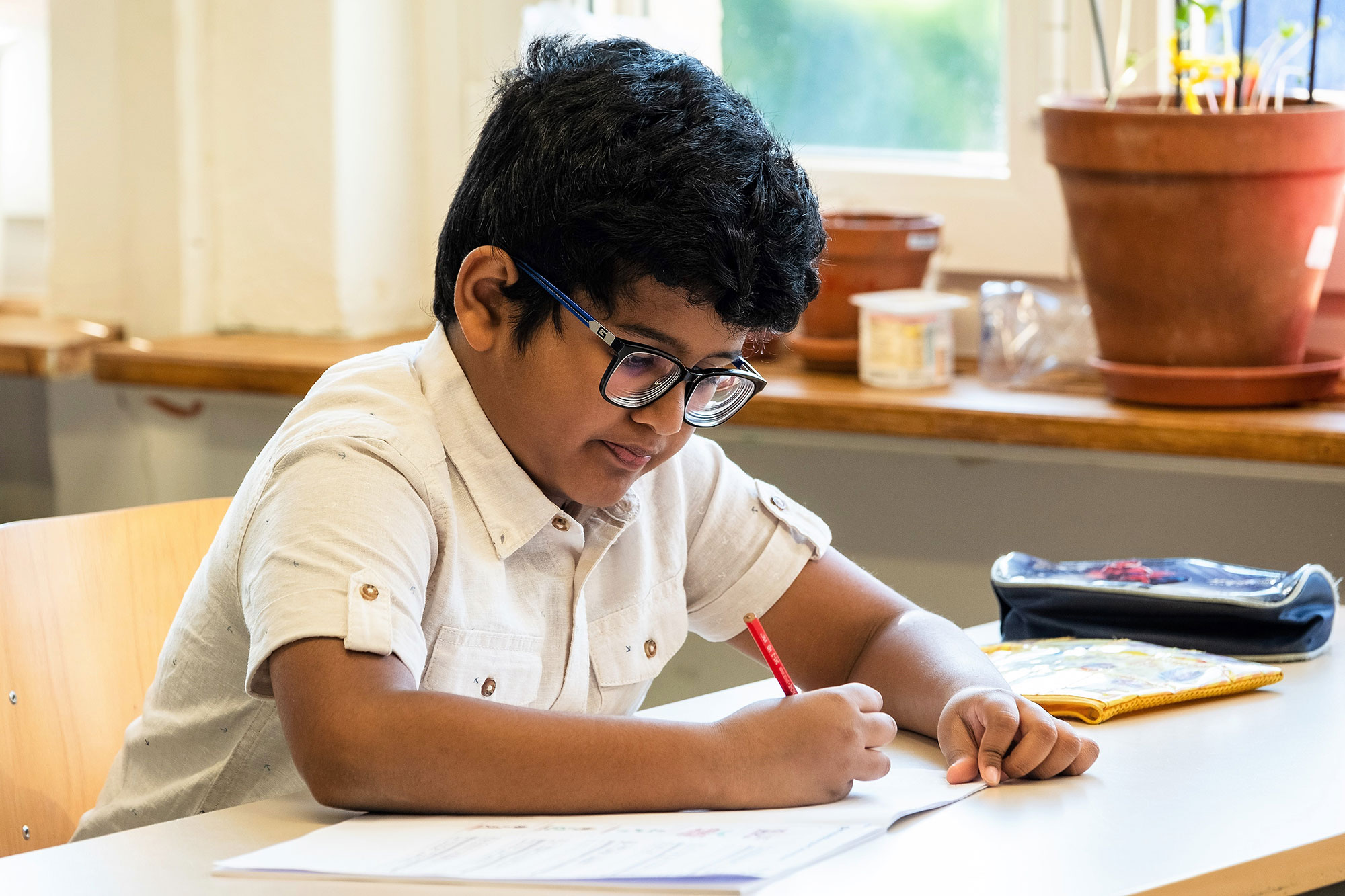 A boy sits at the desk and writes.	