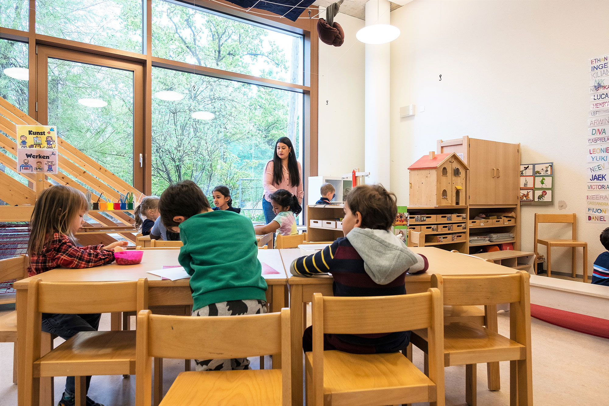 Small children sit at their desks in the kindergarten classroom. 	