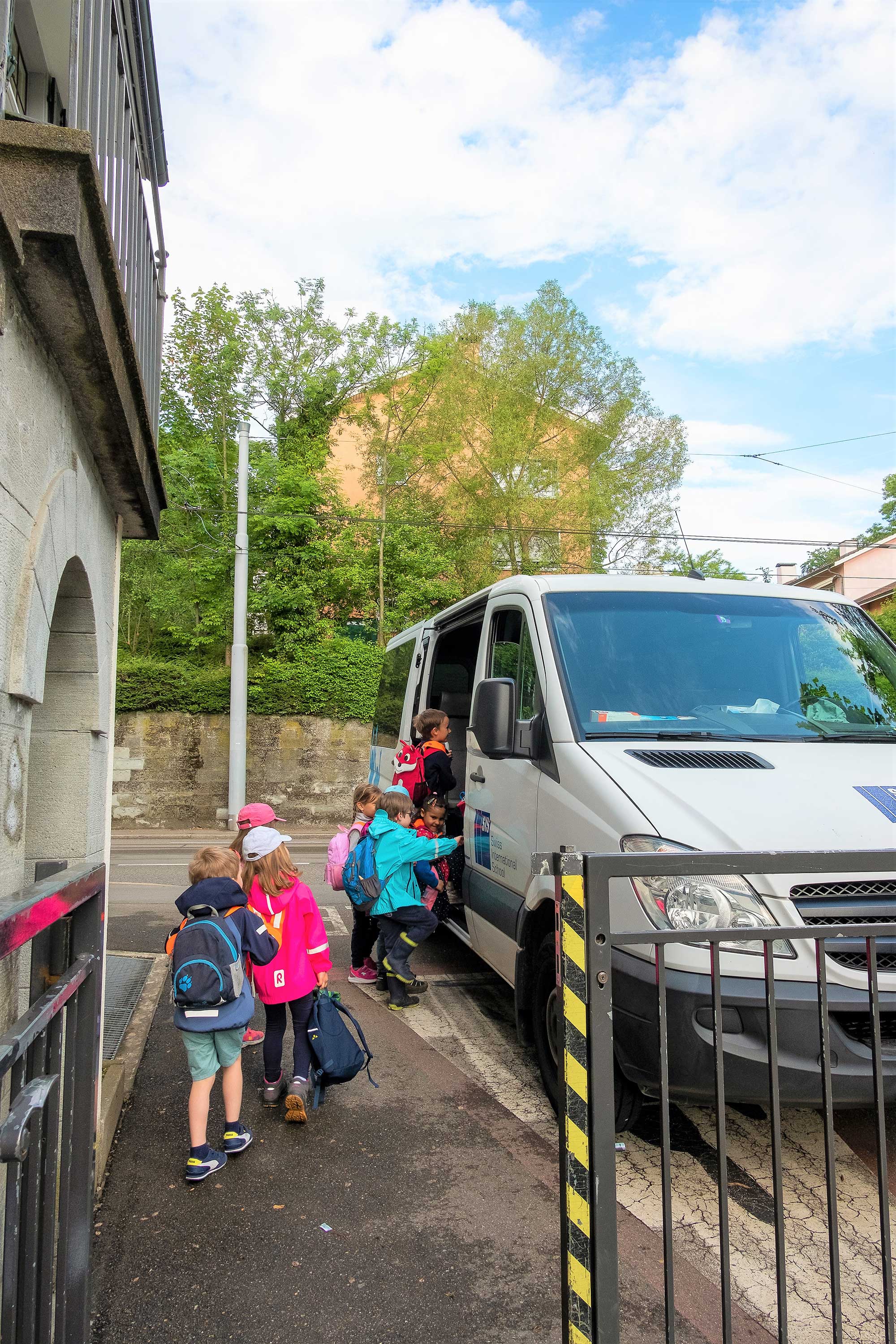 Kindergartenkinder laufen zum Schulbus. Einige Kinder steigen in den Schulbus ein.	