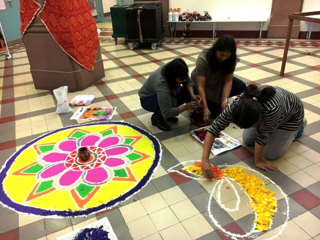 Drei Mädchen gestalten Diwali Zeichnungen auf dem Boden in der Schule.	